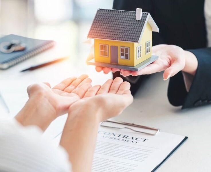 Real estate agent handing over house keys and a model home
